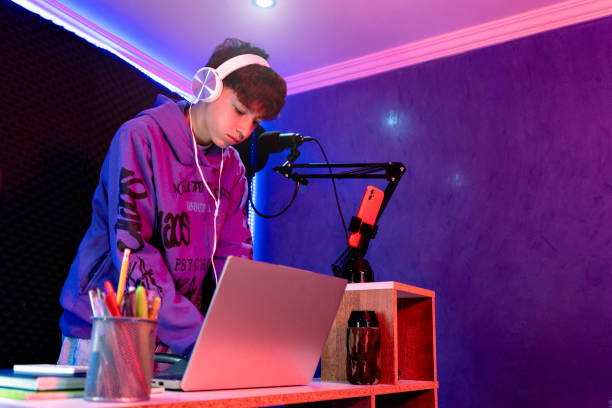 istock Young boy singing with microphone and recording music in home studio. 1603362143