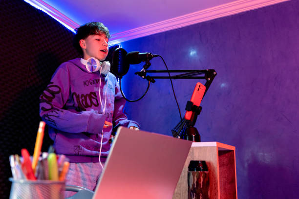 istock Young boy singing with microphone and recording music in home studio. 1603362145