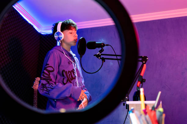 Young boy singing with microphone and recording music in home studio.
