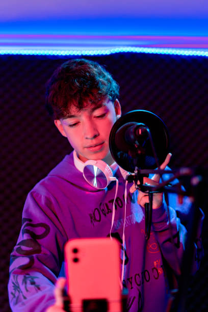 istock Young boy singing with microphone and recording music in home studio. 1603362653