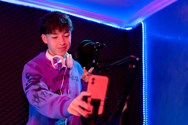 istock Young boy singing with microphone and recording music in home studio. 1603362654
