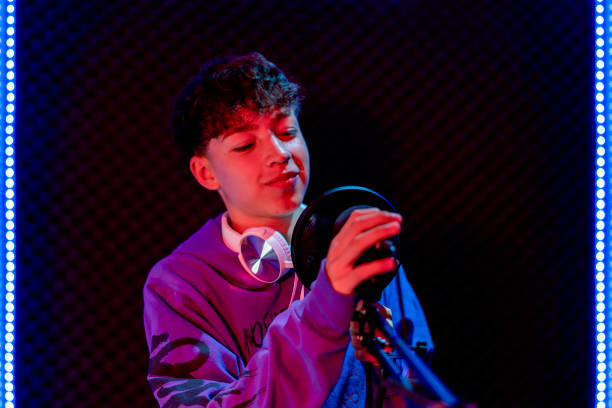 istock Young boy singing with microphone and recording music in home studio. 1603362656