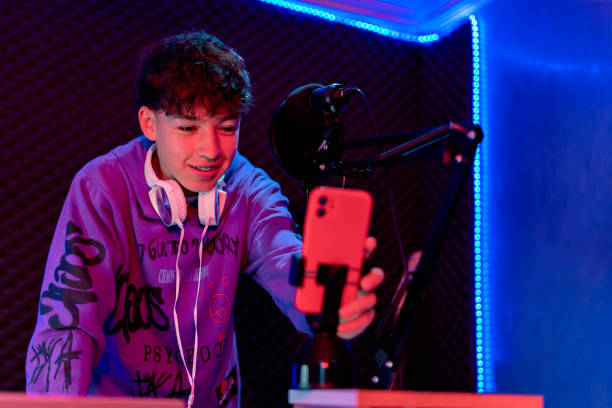 istock Young boy singing with microphone and recording music in home studio. 1603363160