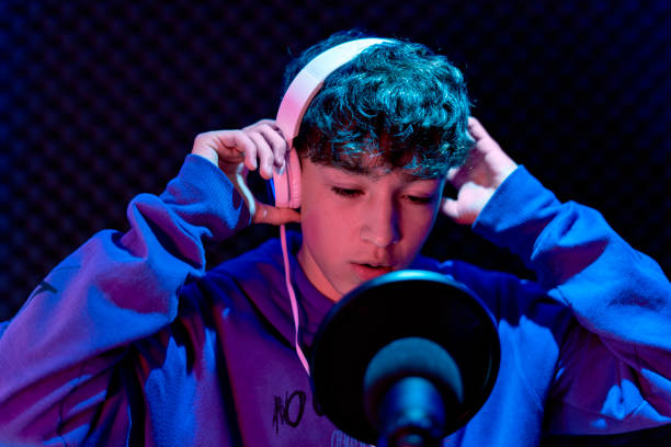 istock Young boy singing with microphone and recording music in home studio. 1603363167