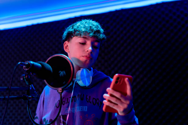 istock Young boy singing with microphone and recording music in home studio. 1603363170