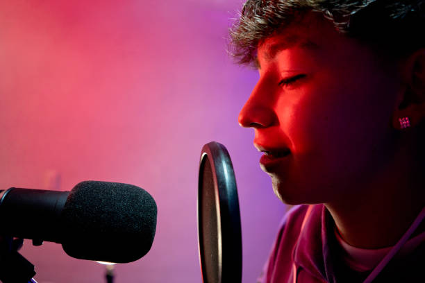 istock Young boy singing with microphone and recording music in home studio. 1603363690