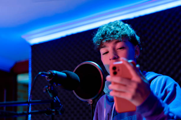 Young boy singing with microphone and recording music in home studio.