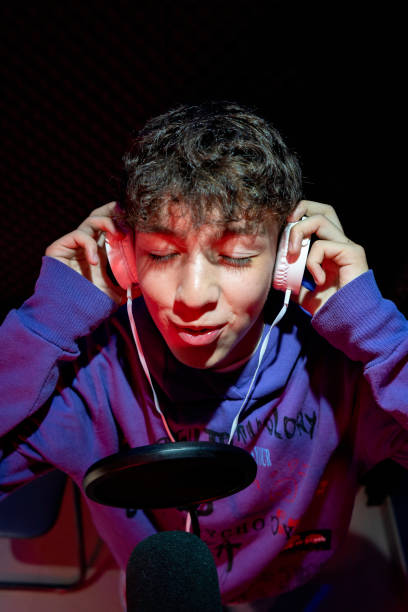 istock Young boy singing with microphone and recording music in home studio. 1603364748