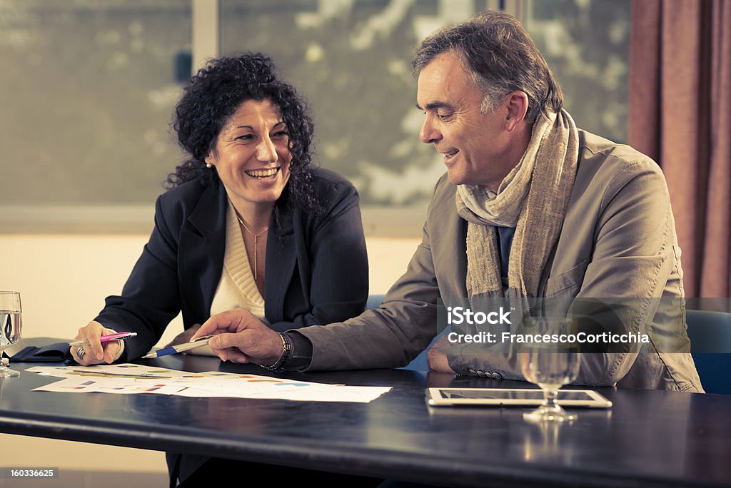 Man and woman talking about business. Man and woman talking about business with a tablet and some paper with graphics inside. Adult Stock Photo