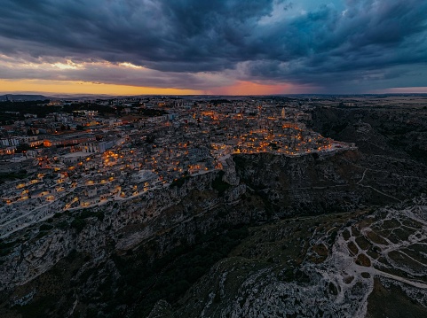 An aerial view of a small village nestled in a hillside, illuminated by the soft light of an overcast sky: Matera, Italy