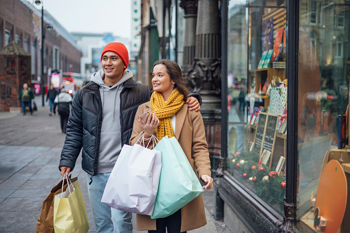 Embark on a captivating journey through the enchanting streets of Newcastle upon Tyne, where the magic of Christmas comes alive in the most delightful ways. This heartwarming image captures the essence of a young couple, ages 20 to 29, as they immerse themselves in a whimsical Christmas shopping adventure
