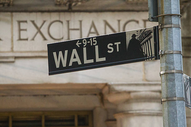 Wall Street and Stock Exchange The New York street sign showing Wall Street outside the New York Stock Exchange. wall street lower manhattan photos stock pictures, royalty-free photos & images