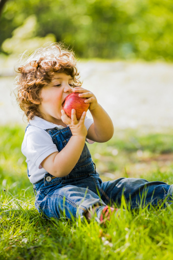 child sitting on the grass eating an apple