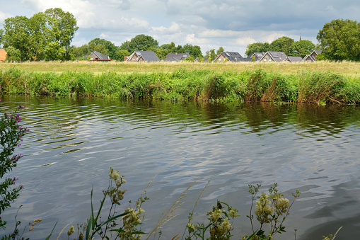 Houses behind the dike along the Vecht River in Laar, Germany, near the Netherlands border