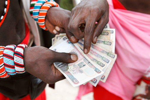 hands of an older woman holding mexican banknotes