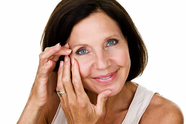 成熟した女性は彼女の顔に触れ - contact lens beauty treatment 50s women ストックフォトと画像