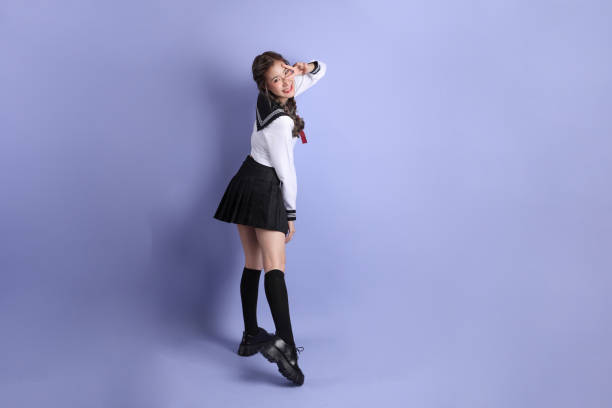 The Asian girl in Japanese student uniform standing on the purple background.