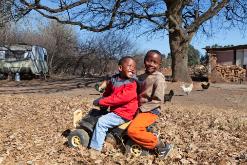 African boys playing with a push car, in an african rural setting.