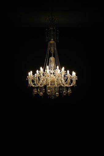 Beautiful crystal chandelier on black background. Vertical photo.
