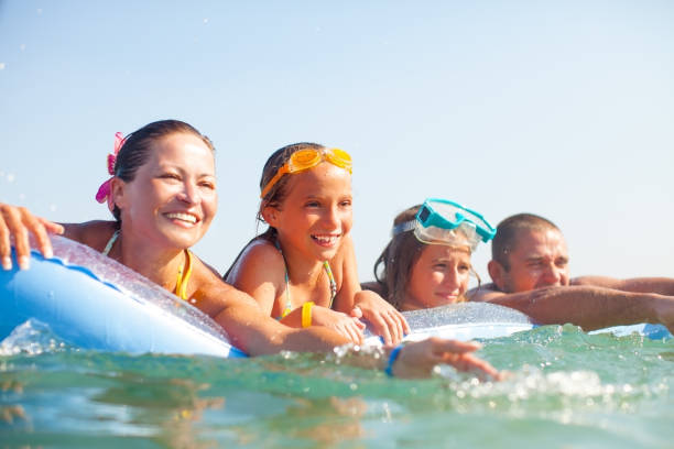 Family in the Sea lying on a inflatable beach mattress Happy Family in the Sea lying on a inflatable beach mattress,with scubas on their heads,having fun scuba diving family stock pictures, royalty-free photos & images
