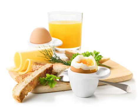 Soft-boiled egg in an eggcup with toast, cheese and orange juice. Healthy breakfast on white background