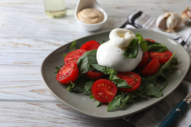 délicieux fromage burrata servi avec des tomates et du basilic sur une table en bois blanc. espace pour le texte - buratta photos et images de collection