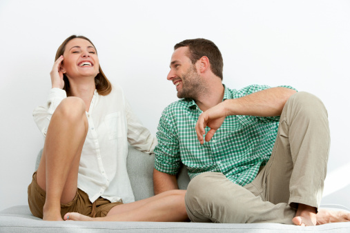 Portrait of handsome couple sharing laughs on couch.
