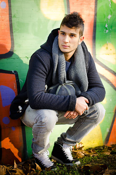 istock Attractive young man sitting against colorful graffiti 160352781