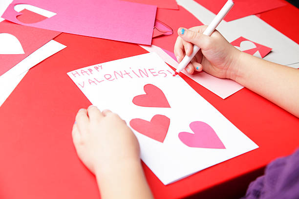 Happy Valentine's Day A young girl makes the finishing touches to her "Happy Valentine's!" card.   crayon drawing photos stock pictures, royalty-free photos & images
