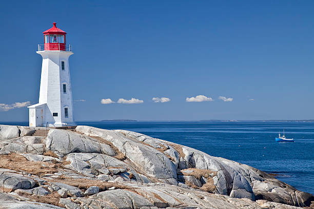 Peggy's Cove Lighthouse Peggy's Cove lighthouse, one of the major tourism destinations in Nova Scotia, Canada.  Lobster boat gathering traps in the background. maritime provinces stock pictures, royalty-free photos & images