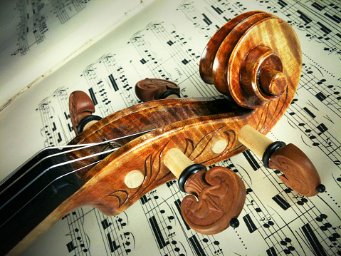 Fancy violin scroll (head) on top of printed music.