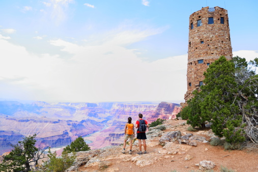 Grand Canyon people hiking. Hiker couple enoying view. Indian Desert View Watchtower, south rim of Grand Canyon, Arizona, USA with view over Colorado River.