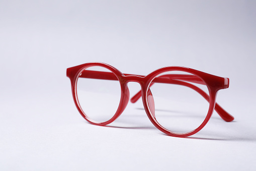 Stylish pair of glasses with red frame on grey background, space for text
