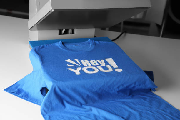 istock Printing logo. Heat press with blue t-shirt on white table 1603553386