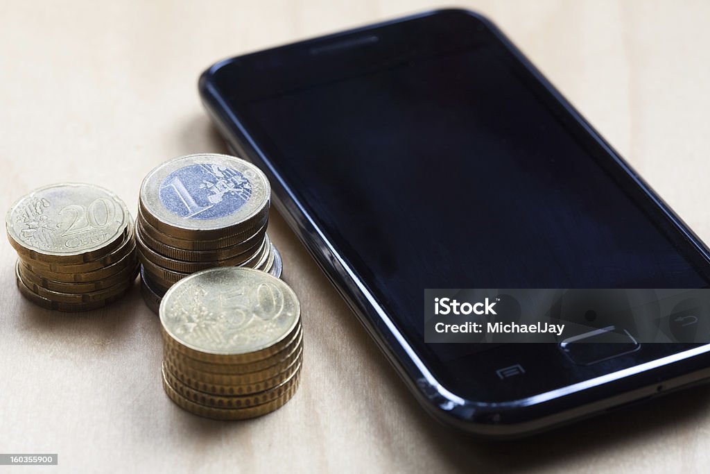 Euro, 50 cent and 20 ct coins with cell phone Concept shot with different Euro coins next to a mobile phone. Blank Stock Photo
