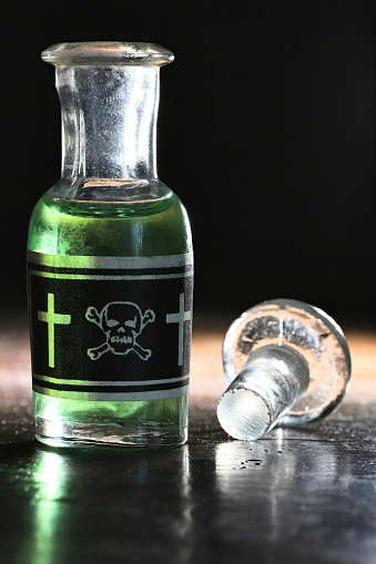 vintage glass bottle of poison on wooden table