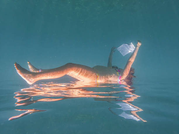 istock Little girl reading a book while under sea 1603663469