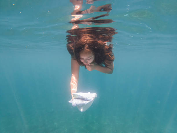 Little girl reading a book while under sea