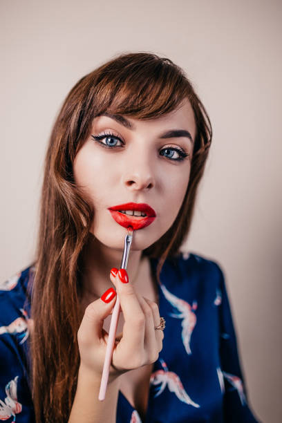 Girl paints her lips with a brush in bright red color - does makeup herself