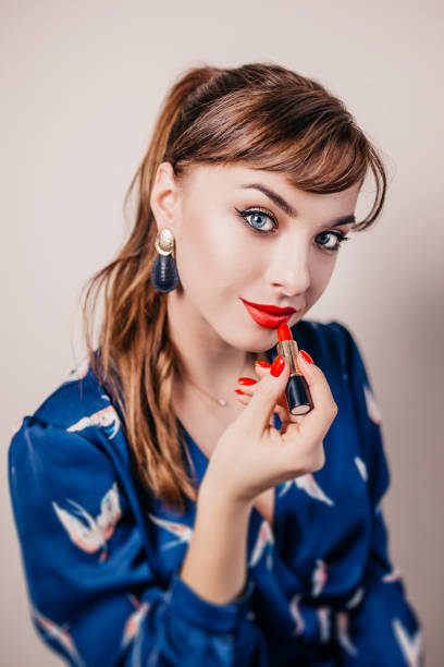 istock Girl paints her lips with bright red lipstick - cosmetics 1603678619