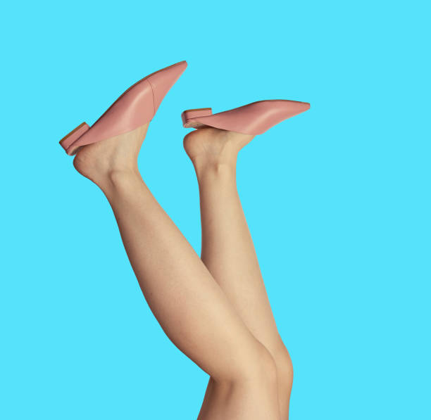 istock Female legs in stylish pink summer mules, isolated on a blue background, upside down. Creative design for fashion blog. 1603684017