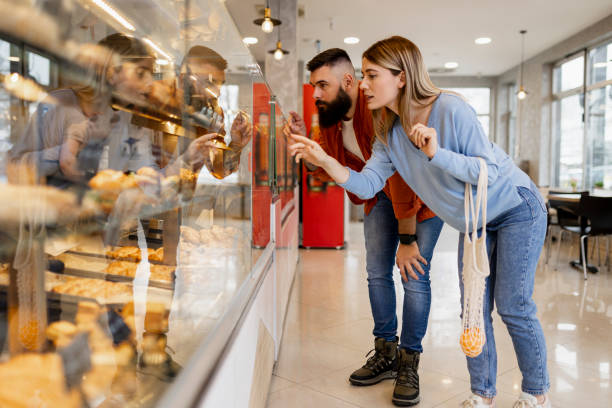 istock Beautiful young couple is choosing pastries and smiling while doing shopping at the bakery 1603687802