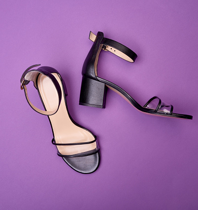 Close up view of cool open-toe women's shoes with block heels, clear vamps, ankle straps and beige insoles, isolated on a purple background. Fashion photography