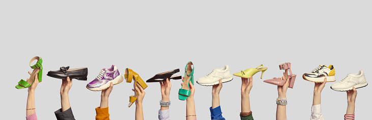 A collage of trendy summer footwear, held by people's hands on an isolated light grey background with copy space. Outlet marketing banner. Shoe sale advertising