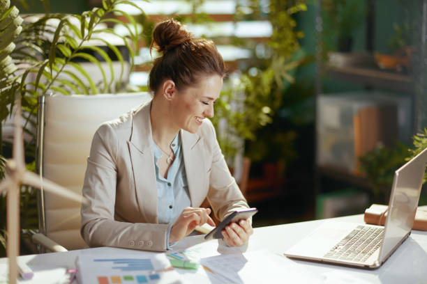 istock smiling bookkeeper woman in green office using smartphone 1603695362