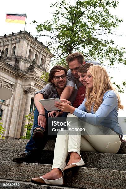 Quattro Amici Guardando Un Tablet - Fotografie stock e altre immagini di Berlino - Germania - Berlino - Germania, PC Ultramobile, Abbigliamento casual