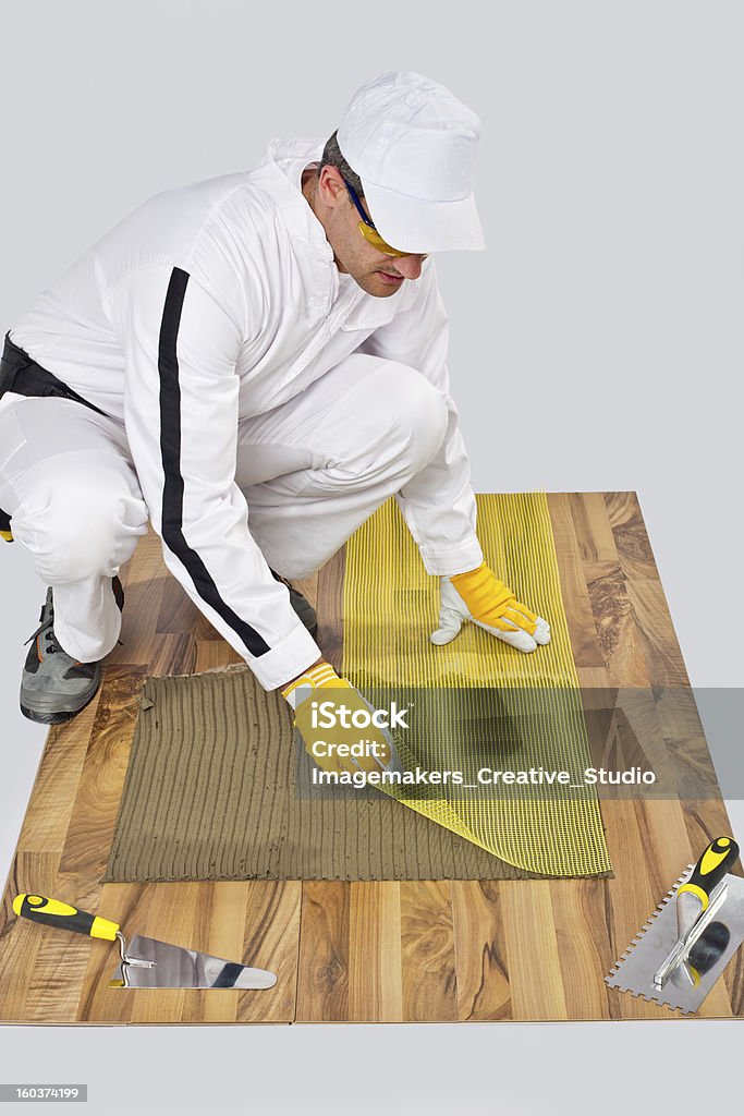 Trabalhador de construção em malha pôr de fibra de vidro com piso de madeira, azulejos adesivo - Foto de stock de Adulto royalty-free