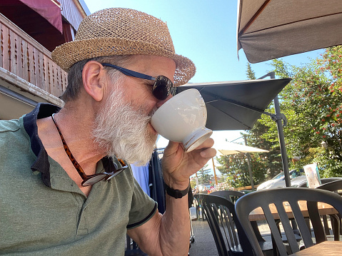 Senior man ejoys an outdoors cup of coffee