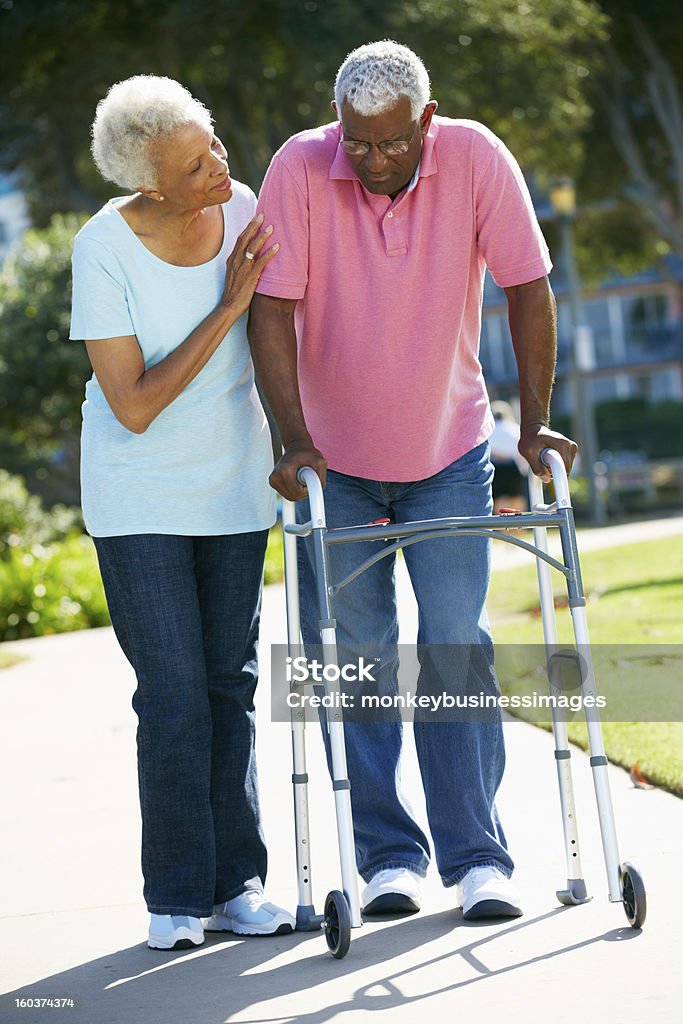 Sênior mulher ajudando marido com uma caminhada de quadro - Foto de stock de Afro-americano royalty-free