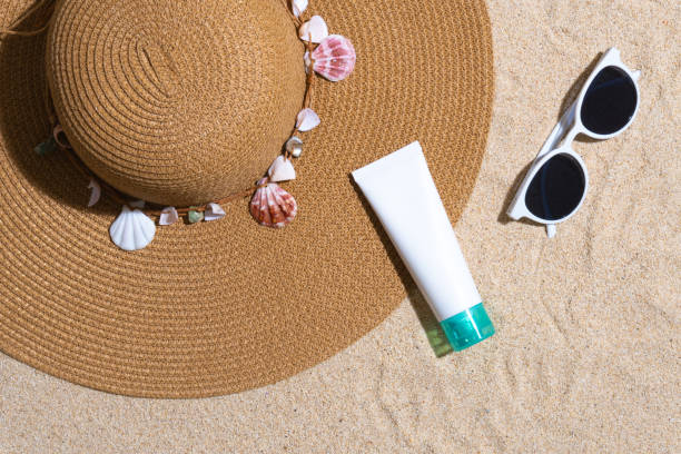 istock Sunscreen container mockup with straw hat, sea shells and sunglasses on sand background 1603751458